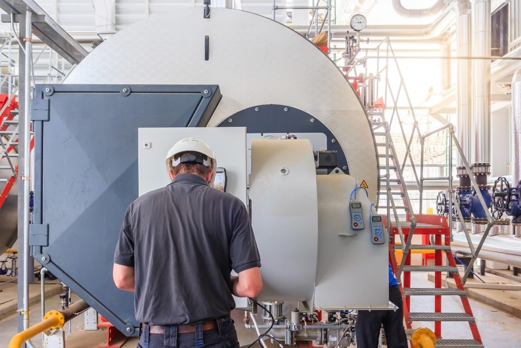 Maintenance engineer working with gas boiler of heating system equipment in a boiler room